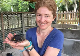 A woman holds a tiny turtle.