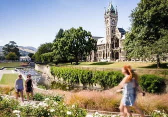 A couple young students walk on campus by a gothic building