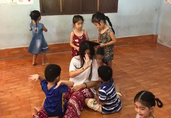 A woman interacts and plays with children.