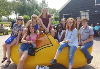 A group of friends poses in a giant, yellow clog in Zaans Schans, Netherlands