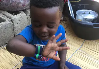 A boy happily looks at his watch.