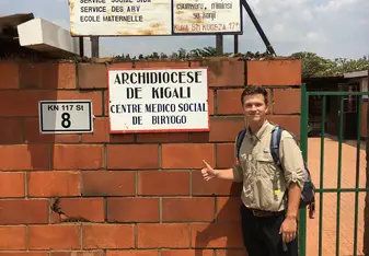 A guy stands near signage of medical center.