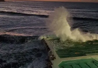 The sun rising in the east next to the Icebergs at Bondi Beach. The waves are crashing into the pool, which is a common, yet beautiful sight to see.