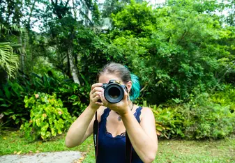 Girl holding Camera with a frog sitting on the lens.