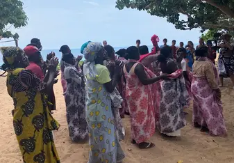 Women singing and dancing in brightly coloured traditional sarongs, during the opening ceremony of the clinic