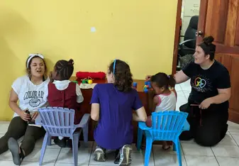 Three SLP students at a table working with kids with disabilities on a fine motor activity.