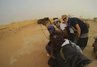 girls in desert taking selfie with camel