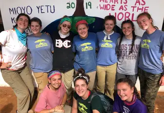 A photo of some of the girls in front of mural we painted at the school. 