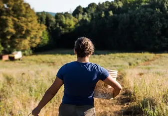 Intern at Work carrying a bucket of water on a farm