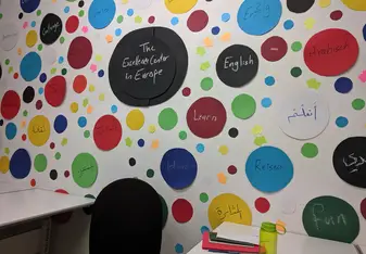 Photo of the wall at the Excellence Center, decorated with words in 3 languages