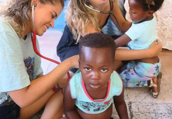 Two Volunteers doing a health screen of the children at the kindergarten