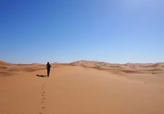 Girl running across dessert dunes on sunny day