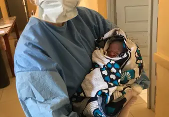 (image of me in surgical gear holding newborn I'd just helped deliver)