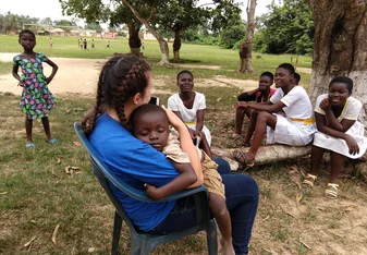 A young Kenyan child child sleeps in the arms of a female Village Book Builders volunteer.