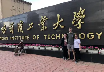 Two of my classmates and I standing in front of the University's sign!