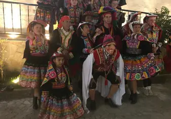 A diverse group of volunteers and locals wearing bright traditional Peruvian carnival clothes.