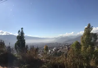 The Cusco landscape in the morning - fog over the city surrounded by greenery and mountains.