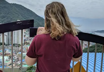 picture of a girl looking out over a crowded colorful village and the sea