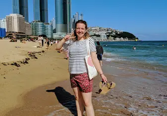 girl standing on a beach with buldings in the background