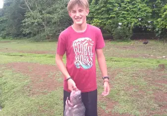 Teen boy stands with large Tilapia fish