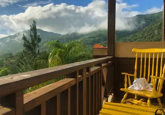 View of green mountains covered in clouds from balcony. 