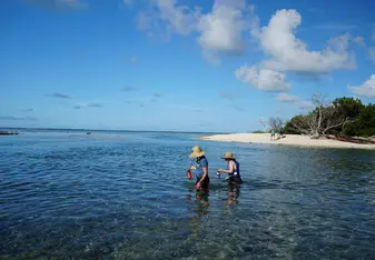 two people wade through  ocean water 