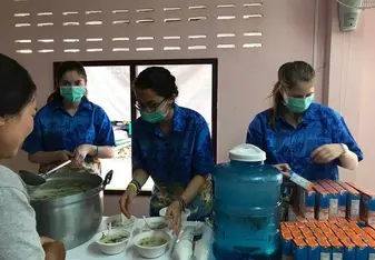 3 Team members are serving soup from a stand in a hospital.