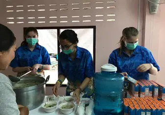 3 Team members are serving soup from a stand in a hospital.