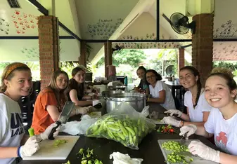 Team members are sitting on a table, preparing food to distribute in the village. 