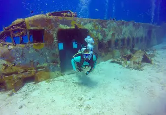 Diver exiting sunken plane wreck.