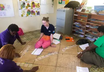 Zoe is sitting with 3 Community Health Workers on a mat, they are doing an activity that matches up cards