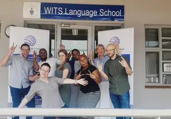 Group of teachers standing in front of a Wits Language School sign