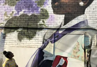 Girl looking at large wall mural of young girl in traditional Korean dress (hanbok)