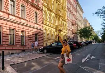 Girl standing in the street, posing in front of colorful buildings.