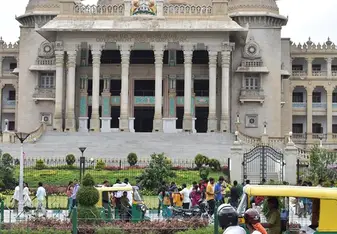 Government building in Bangalore with Indian flag flying. Two people on a moped are stopped to admire the building.