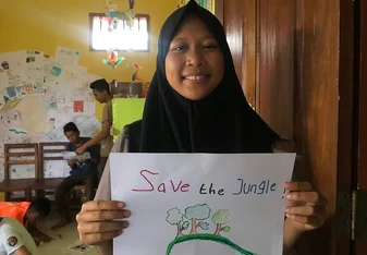 Student holding a 'Save the Jungle' Poster