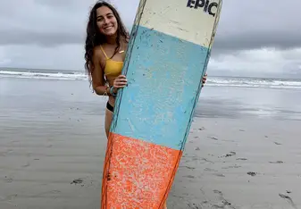 Me holding a surfboard at Jacó beach, Costa Rica where I took surf lessons through USAC