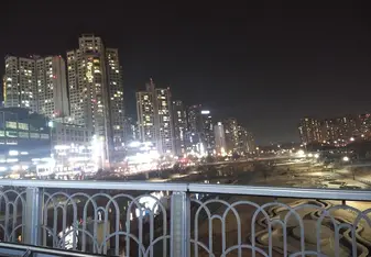 It is a city outside of Seoul; a view from a walking bridge looking over at colorful skyscrapers. 