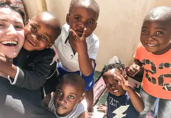 Várias crianças fazendo pose para foto e abrançando a voluntária.