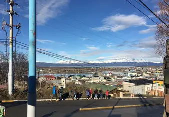 Line of people walking with city and mountain in background, big blue sky above