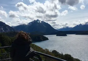 picture of girl with back facing camera in front of mountain and lake scenery