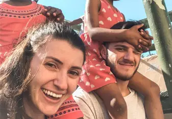 Duas crianças sentadas nos pescoços de dois voluntários.