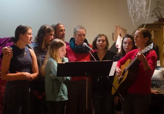 Participant clustered around a microphone and performing as backup singers for a local artist