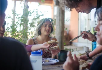 Participant buttering toast during a community dinner.