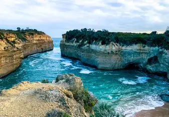 Cliffs sectioning off vibrant blue water and a smooth beach from the open ocean.