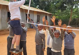 Greg putting up the volleyball net with the help of eager students.