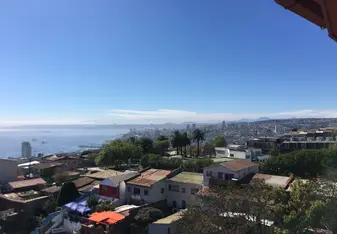A window view of colorful Valparaiso and the Pacific, with Vina del Mar on the horizon. 