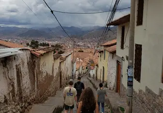 Students walk a street with old buildings and mountains in the background.