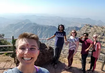 A group of friends smiles in front of the cliffs of Mahabaleshwar.