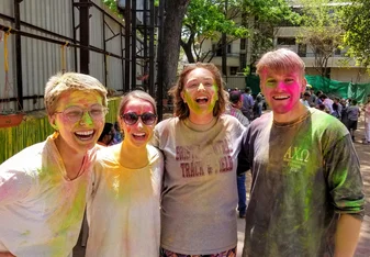 A group of friends smiles, covered in colored powder, after playing Holi with local schoolchildren in Pune.